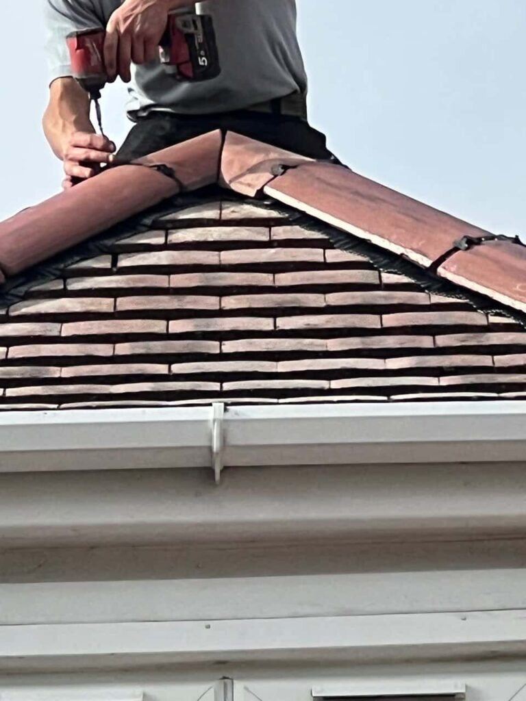This is a photo of one of the operatives of LJ Roofing Haydon Wick installing new ridge tiles
