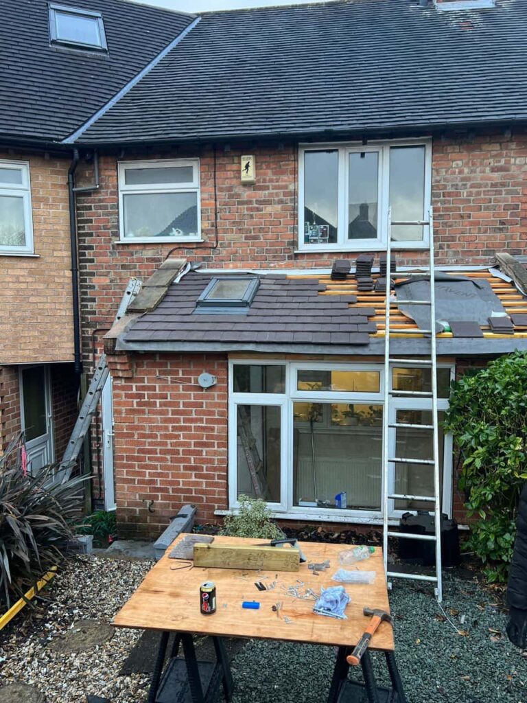 This is a photo of a roof extension that is having new roof tiles installed. This is a photo taken from the roof ridge looking down a tiled pitched roof on to a flat roof. Works carried out by LJ Roofing Haydon Wick
